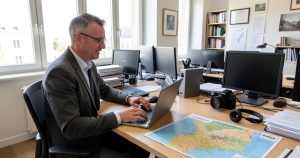 Journaliste de presse locale rédigeant un article sur ordinateur dans une rédaction régionale